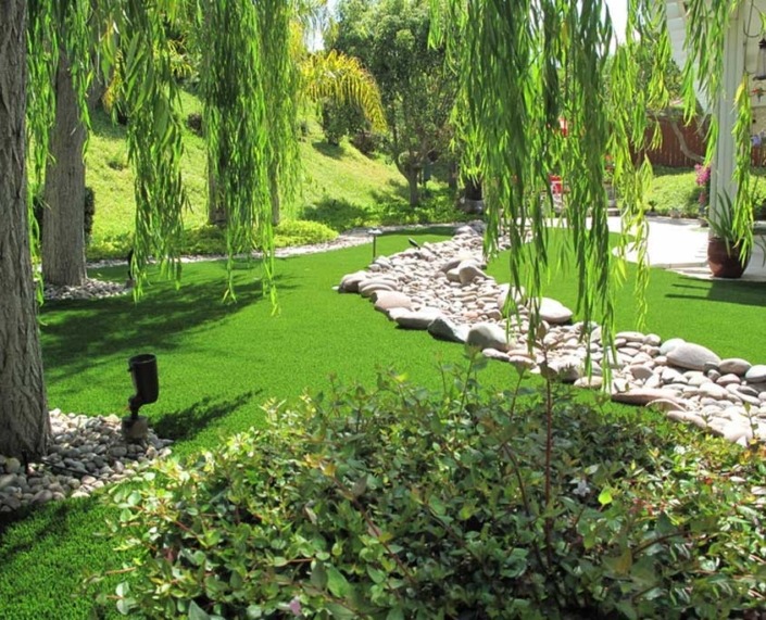 artificial grass landscape with shrubbery surrounding it