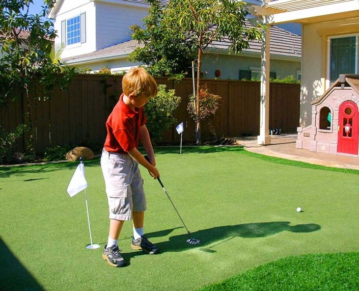 little boy putting on an outdoor artificial putting green surface