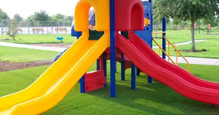 close up of 2 slides installed atop artificial turf
