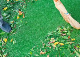 close up of person cleaning artificial grass debris with a broom.
