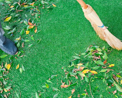 close up of person cleaning artificial grass debris with a broom.